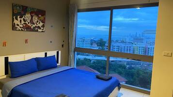 Un dormitorio con una cama grande, vistas a la ciudad y un cuadro en la pared.