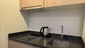 A compact kitchen with a black induction cooktop, a stainless steel sink, and a kettle. - Unixx South Pattaya Condominium (Pattaya)