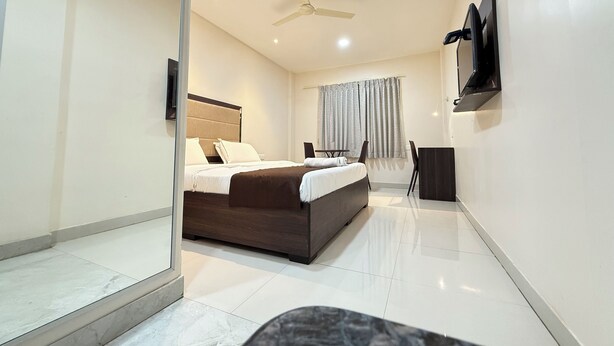 A modern hotel room with a bed, a TV, a ceiling fan, and a window with curtains. - HOTEL CENTER POINT (Bhubaneshwar)