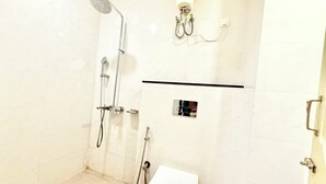 A bathroom with a shower, toilet, and a towel rack. - HOTEL CENTER POINT (Bhubaneshwar)