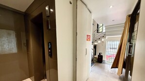 A hallway with an elevator, a lift button, a staircase, and a gas cylinder. - HOTEL CENTER POINT (Bhubaneshwar)