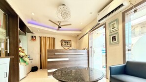 A hotel reception area with a wooden reception desk, a round marble table, a ceiling fan, and a blue sofa. - HOTEL CENTER POINT (Bhubaneshwar)