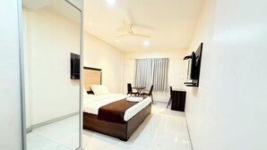 A modern hotel room with a large bed, a desk, a chair, a TV, and a ceiling fan. - HOTEL CENTER POINT (Bhubaneshwar)