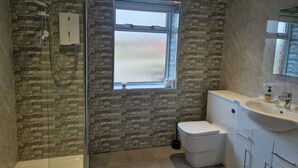 A bathroom with a shower, toilet, sink, and window. - 2 Newmill (Stanley)