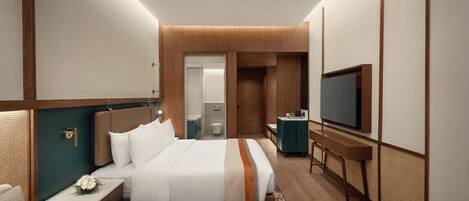 A hotel room with a bed, bedside table, TV, and a bathroom visible through an open door.