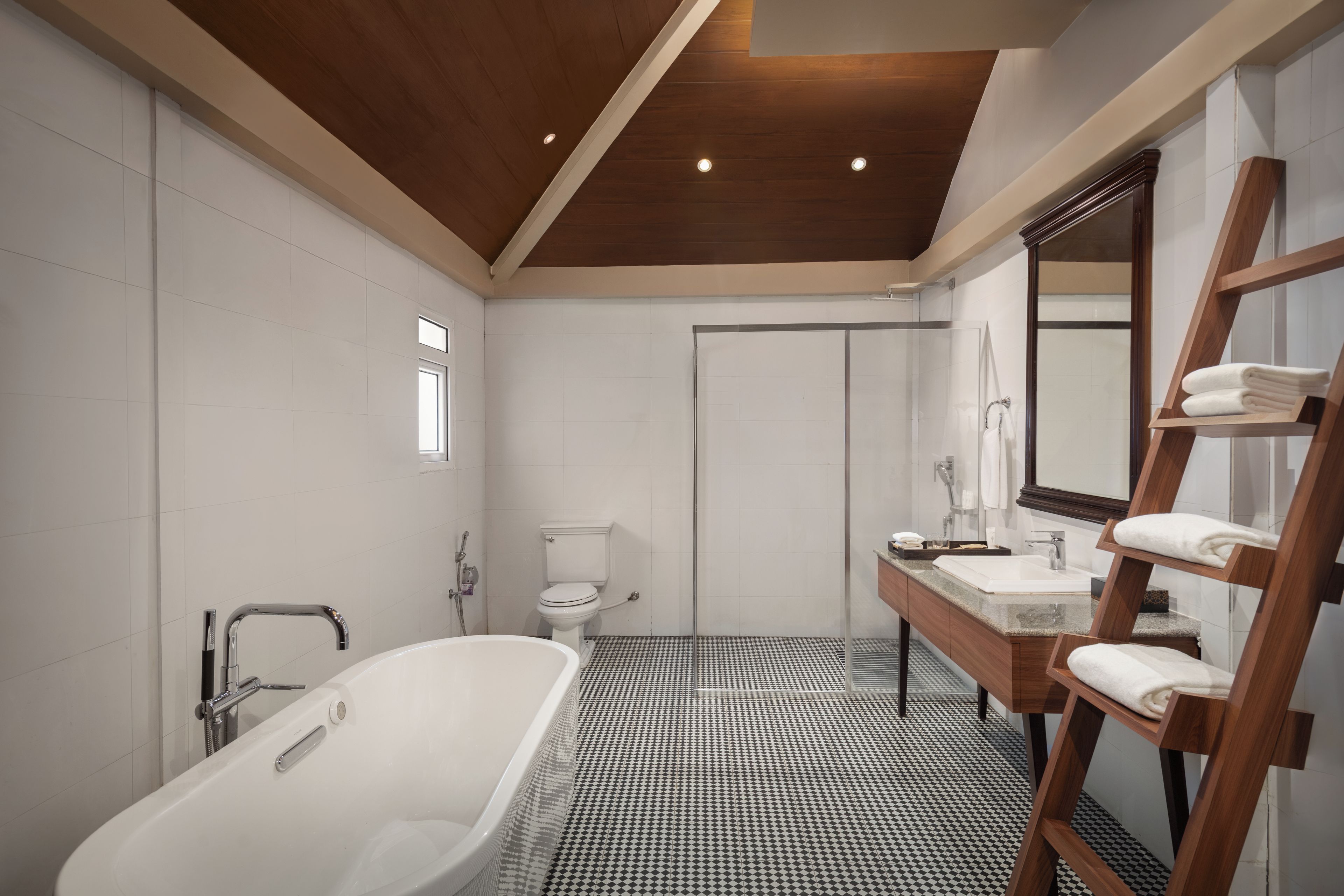 Une salle de bain moderne avec une baignoire sur pieds, des toilettes et un meuble-lavabo doté d’un miroir et d’un porte-serviettes.