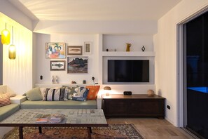 Ein Wohnzimmer mit Sofa, Couchtisch, Fernseher und Kunstwerk an der Wand.