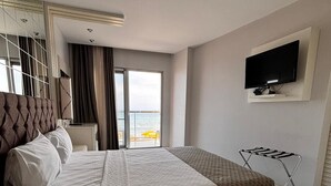 A hotel room with a large bed, a TV mounted on the wall, and a view of the sea through the window. - Sarehotel (Kusadasi)