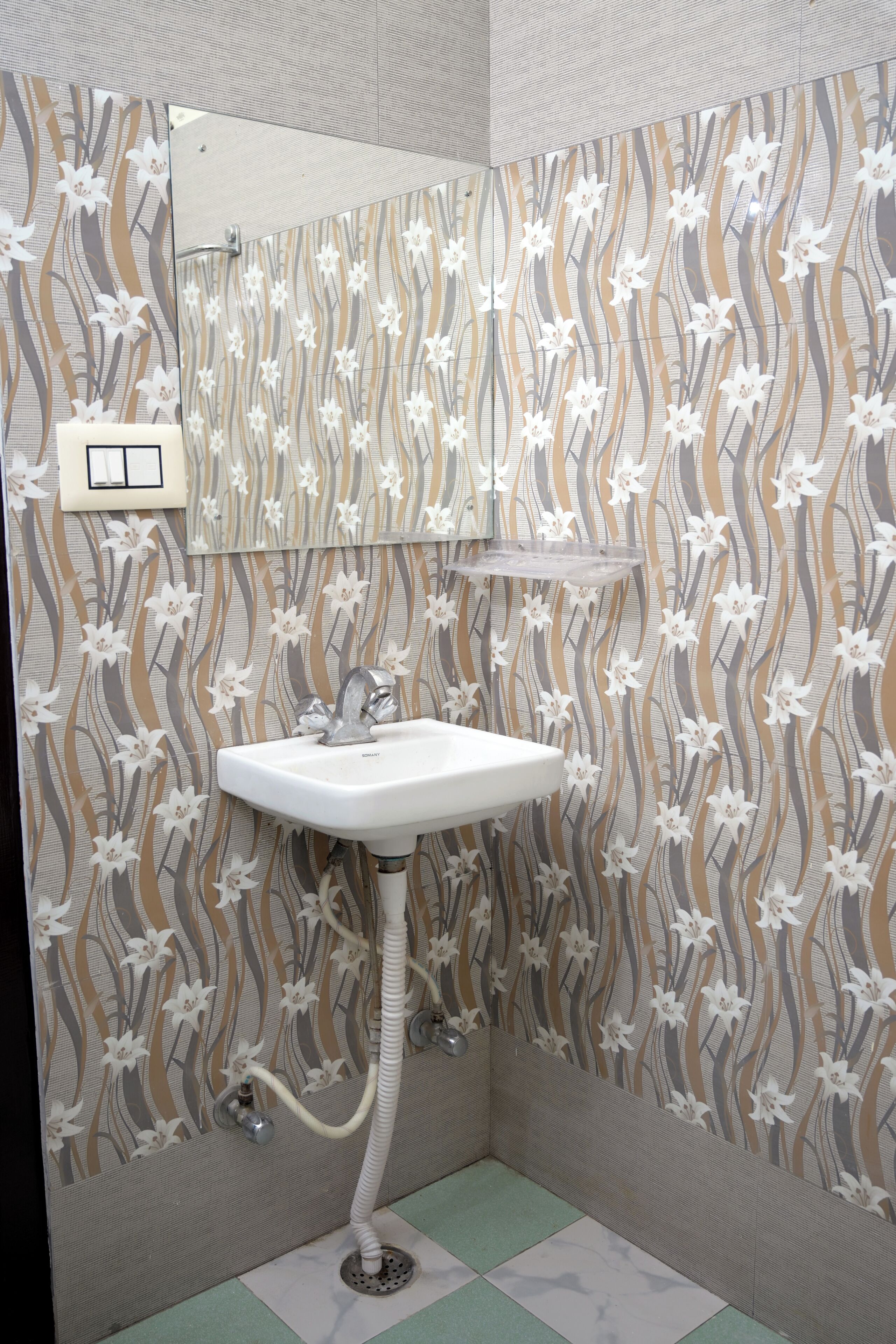 A bathroom with a patterned wallpaper, a white sink, a mirror, and a towel rack.