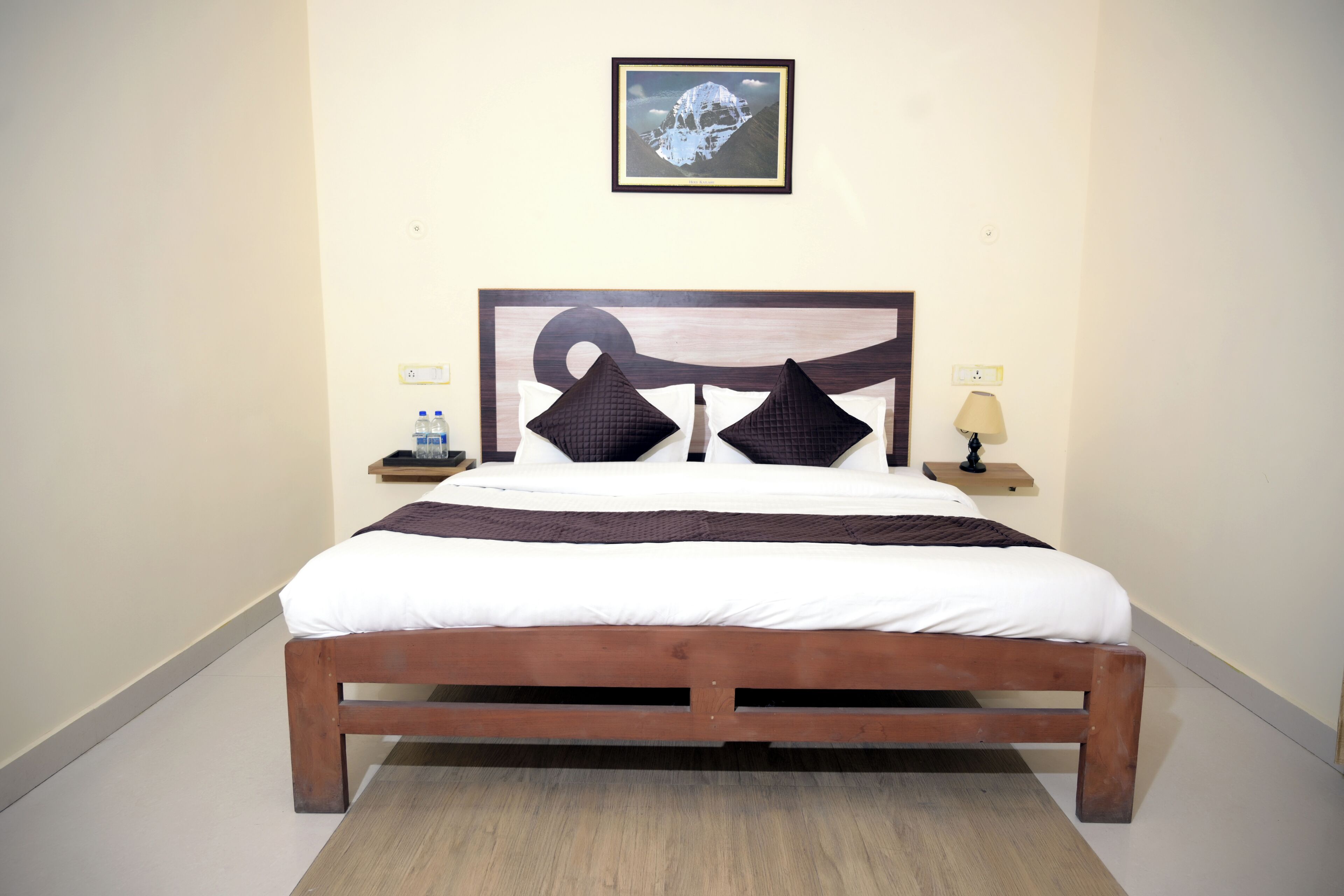 Una cama con estructura de madera, ropa de cama blanca y dos mesitas de noche con lámparas.