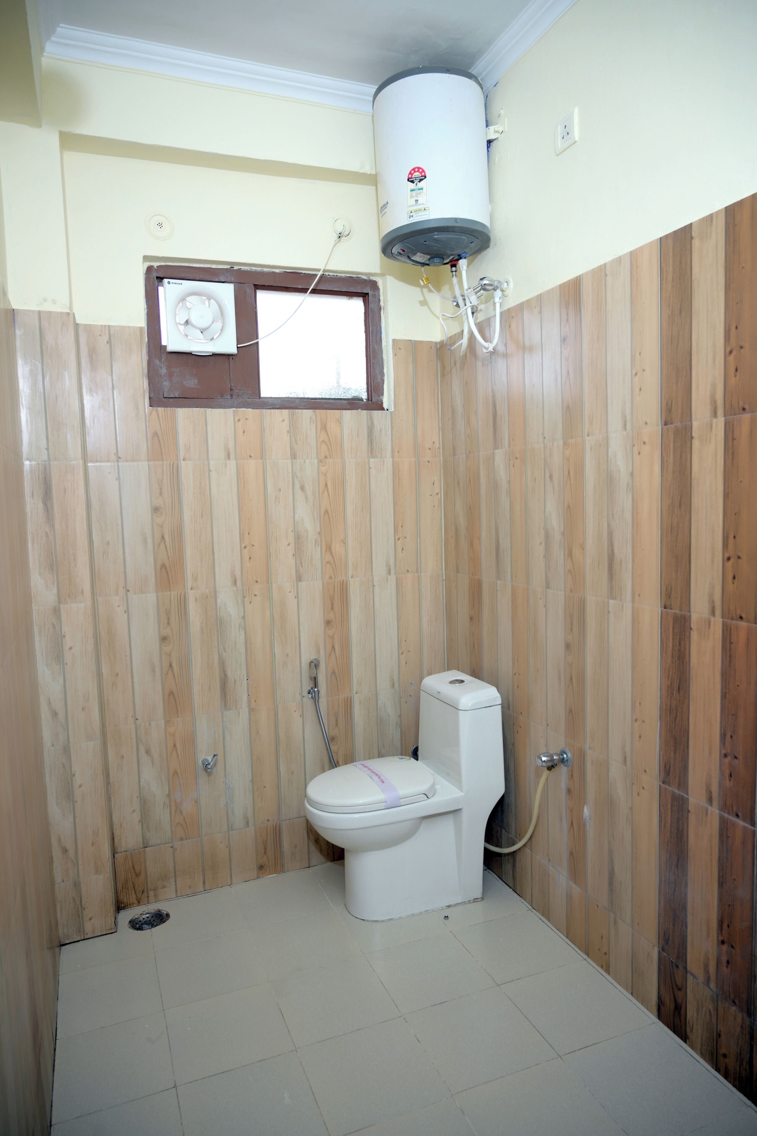 A bathroom with a toilet, a water heater, and a window.