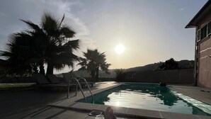 A poolside view with a reclining chair, palm trees, and a clear sky. - Quiet house with private pool in Godinhaços, northern Portugal. (Godinhaços)