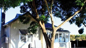 Une maison avec un grand arbre devant, une cour clôturée et un garage.