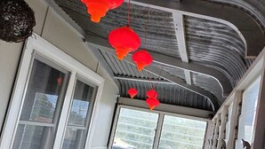 Un petit coin repas avec une table et des chaises, une fenêtre avec des stores et des lanternes rouges suspendues au plafond.