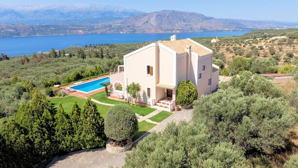Una casa a due piani con piscina, immersa nel verde e vista mare.