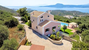 Una casa a due piani con piscina, immersa nel verde e vista mare.