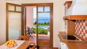 Una cucina con vista su piscina e montagne, una zona pranzo con tavolo e sedie e una ventola a soffitto.