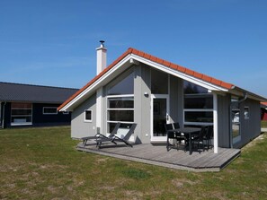 A modern house with a deck, large windows, and a chimney. - 4 Star Holiday Home in Grossenbrode (Grossenbrode)