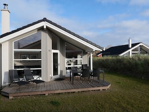A modern house with a deck, a kitchen, and a dining area with outdoor furniture. - 4 Star Holiday Home in Grossenbrode (Grossenbrode)