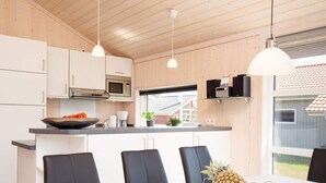 A modern kitchen with white cabinets, a microwave, and a dining area with a table and chairs. - 4 Star Holiday Home in Grossenbrode (Grossenbrode)