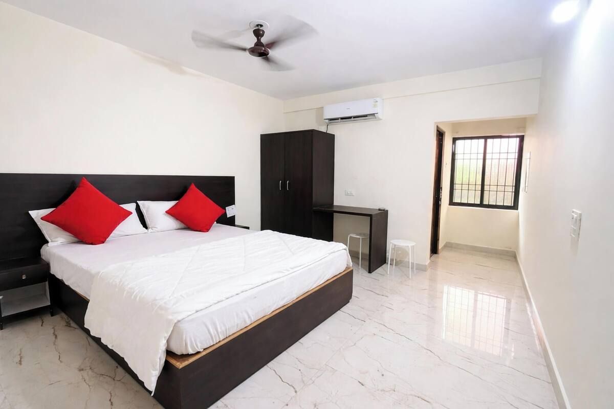 Une chambre à coucher comprenant un lit, une armoire, un bureau et un ventilateur de plafond.