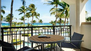 Ein Balkon mit Blick auf den Ozean, Palmen und einen Pool.