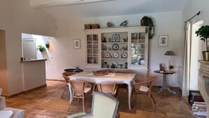 En spiseplads med et bord, stole, et skab med glasdøre og en pejs.