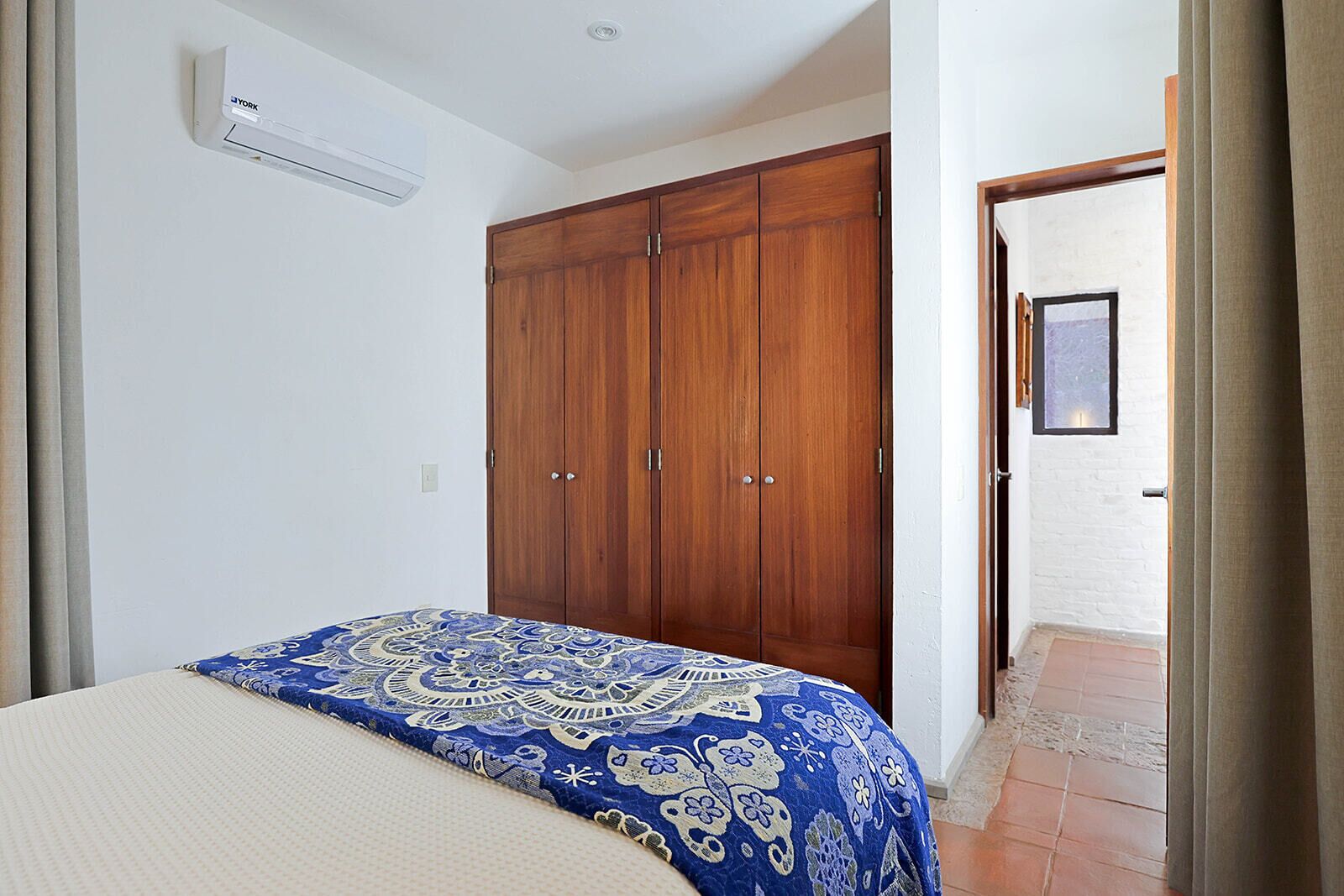 Un dormitorio con cama, armario, aire acondicionado y puerta que da a otra habitación.