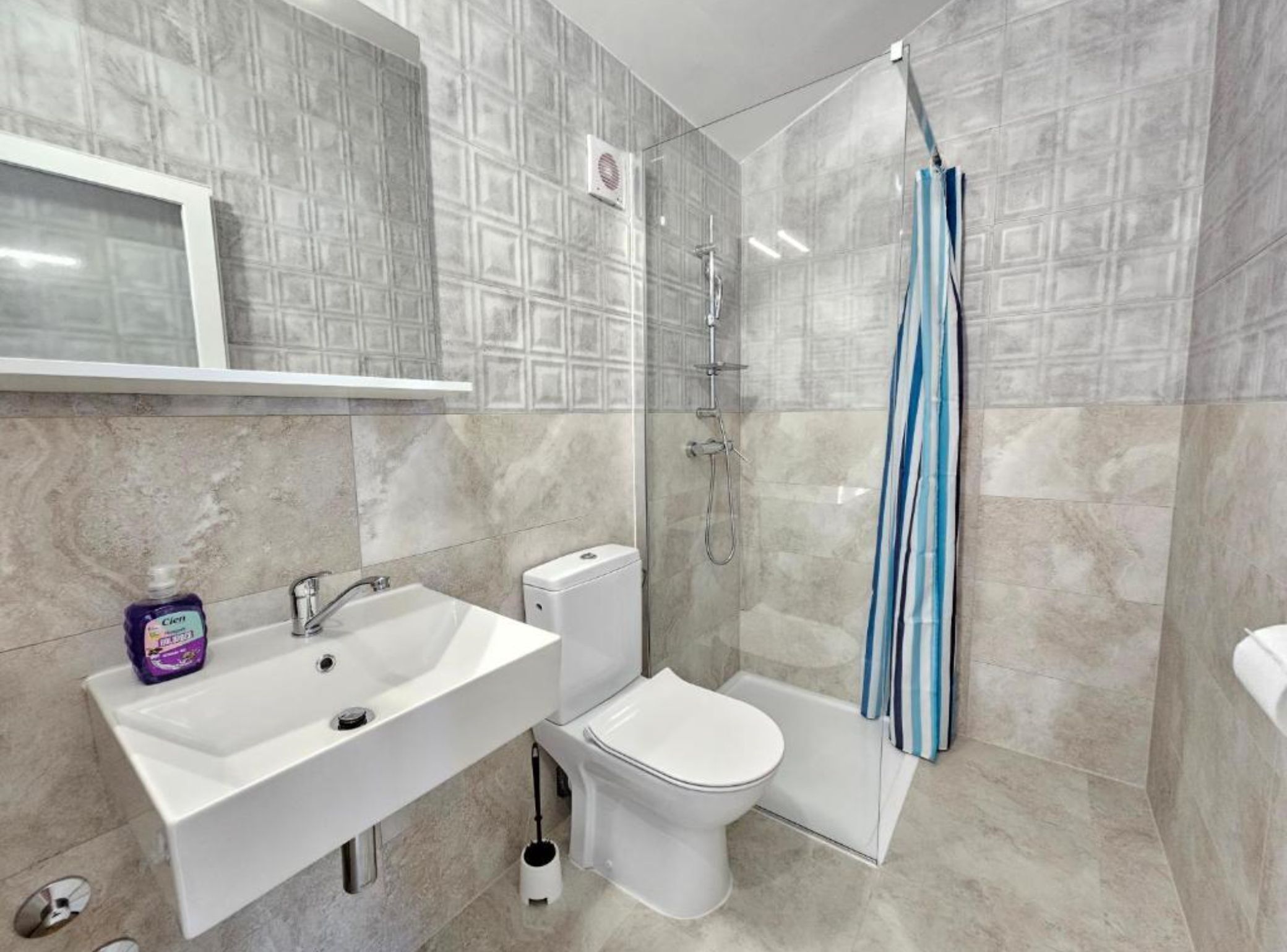 A bathroom with a sink, toilet, shower, and a towel rack.