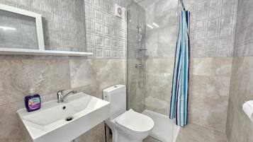 A bathroom with a sink, toilet, shower, and a towel rack.