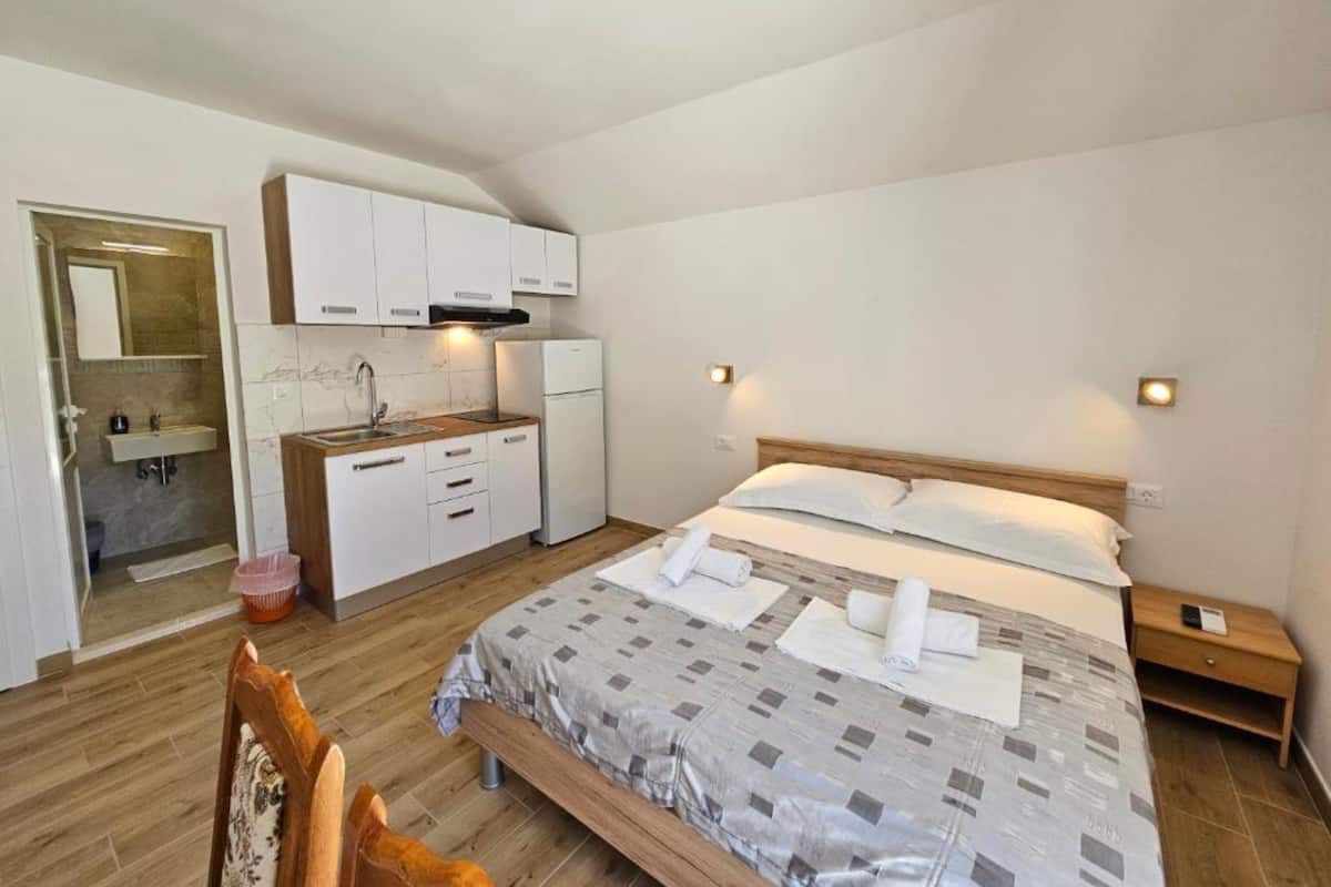 A bedroom with a bed, bedside table, and a small wooden nightstand.
