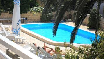 Una piscina con sillones de playa y sombrillas.