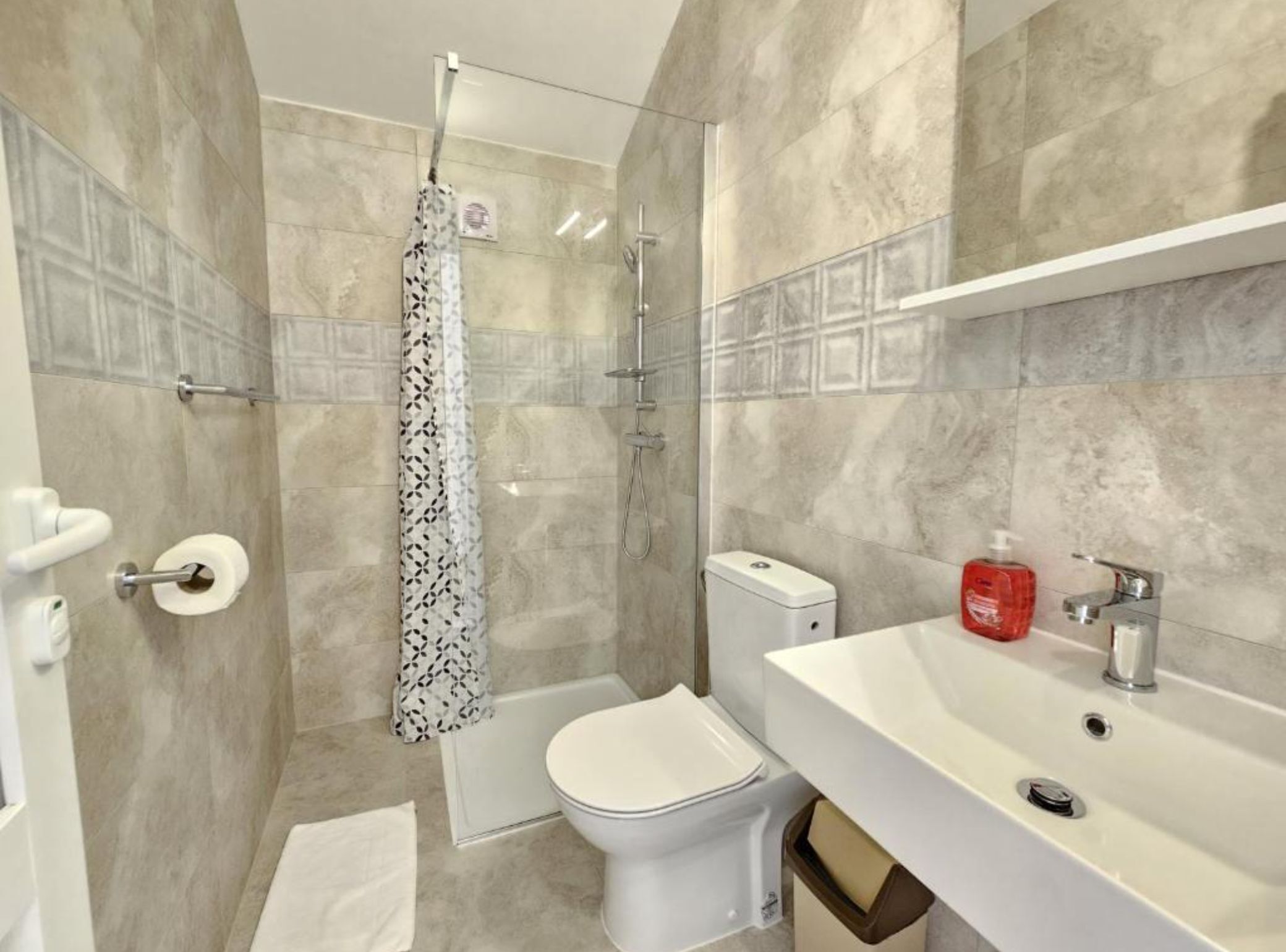 A bathroom with a shower, toilet, and sink.