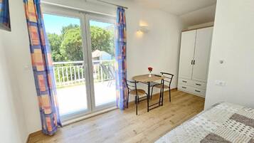 Un dormitorio con cama, una mesita con sillas, un balcón con vistas y un armario.