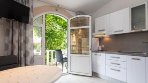 A modern kitchen with white cabinets, a built-in oven, and a large window overlooking greenery. - Adriatic Guesthouse Balota With Shared Pool (Viganj)