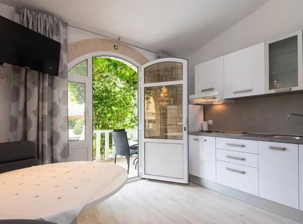 A modern kitchen with white cabinets, a built-in oven, and a large window overlooking greenery. - Adriatic Guesthouse Balota With Shared Pool (Viganj)