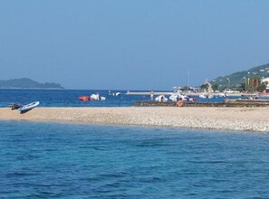 Un paysage côtier avec des bateaux, une plage et une colline au loin.
