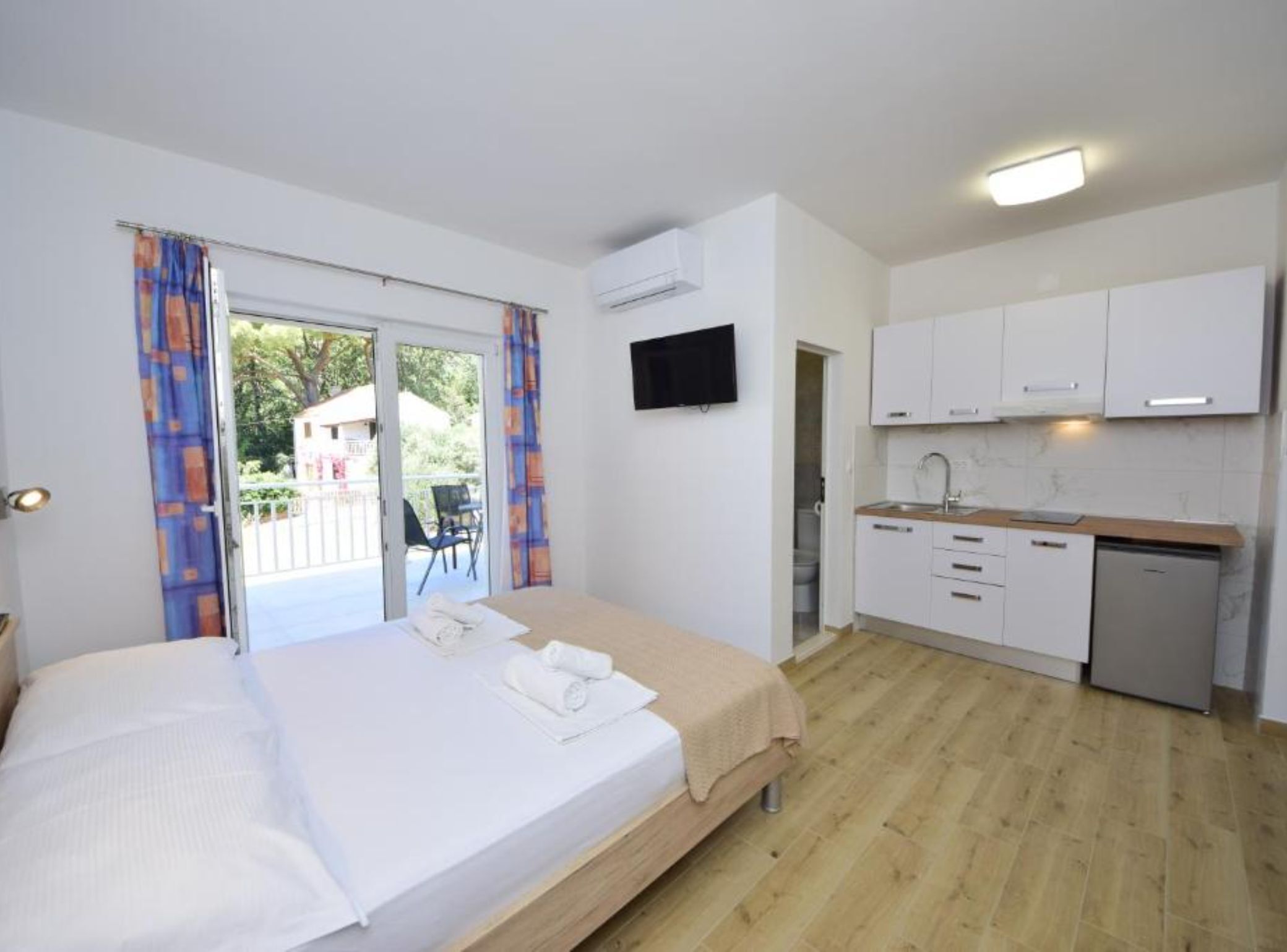 A bedroom with a bed, a bathroom, and a kitchenette.