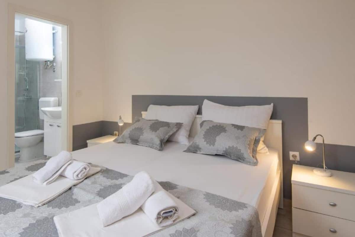 A neatly made bed with pillows, a bedside lamp, and a towel on the floor.
