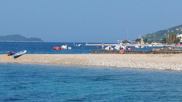 A coastal scene with boats, a beach, and a distant hill. - Adriatic Guesthouse Balota With Shared Pool (Viganj)