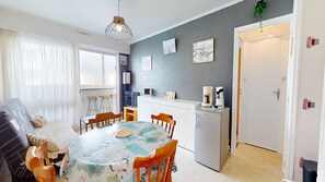 A compact living space with a dining area, kitchenette, and a door leading to another room. - Grande Maree - Apartment Sea View, 100m from the beach (Saint-Hilaire-de-Riez)