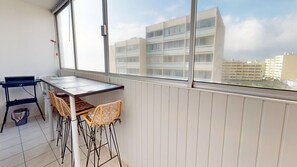 A balcony with a table and chairs, a radiator, and a view of buildings. - Grande Maree - Apartment Sea View, 100m from the beach (Saint-Hilaire-de-Riez)