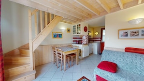 Un intérieur chaleureux avec un escalier en bois, un coin repas, une kitchenette et un salon doté d’un canapé.