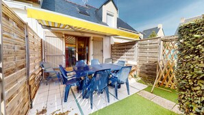 Une terrasse avec une table et des chaises, une clôture en bois et un auvent jaune.