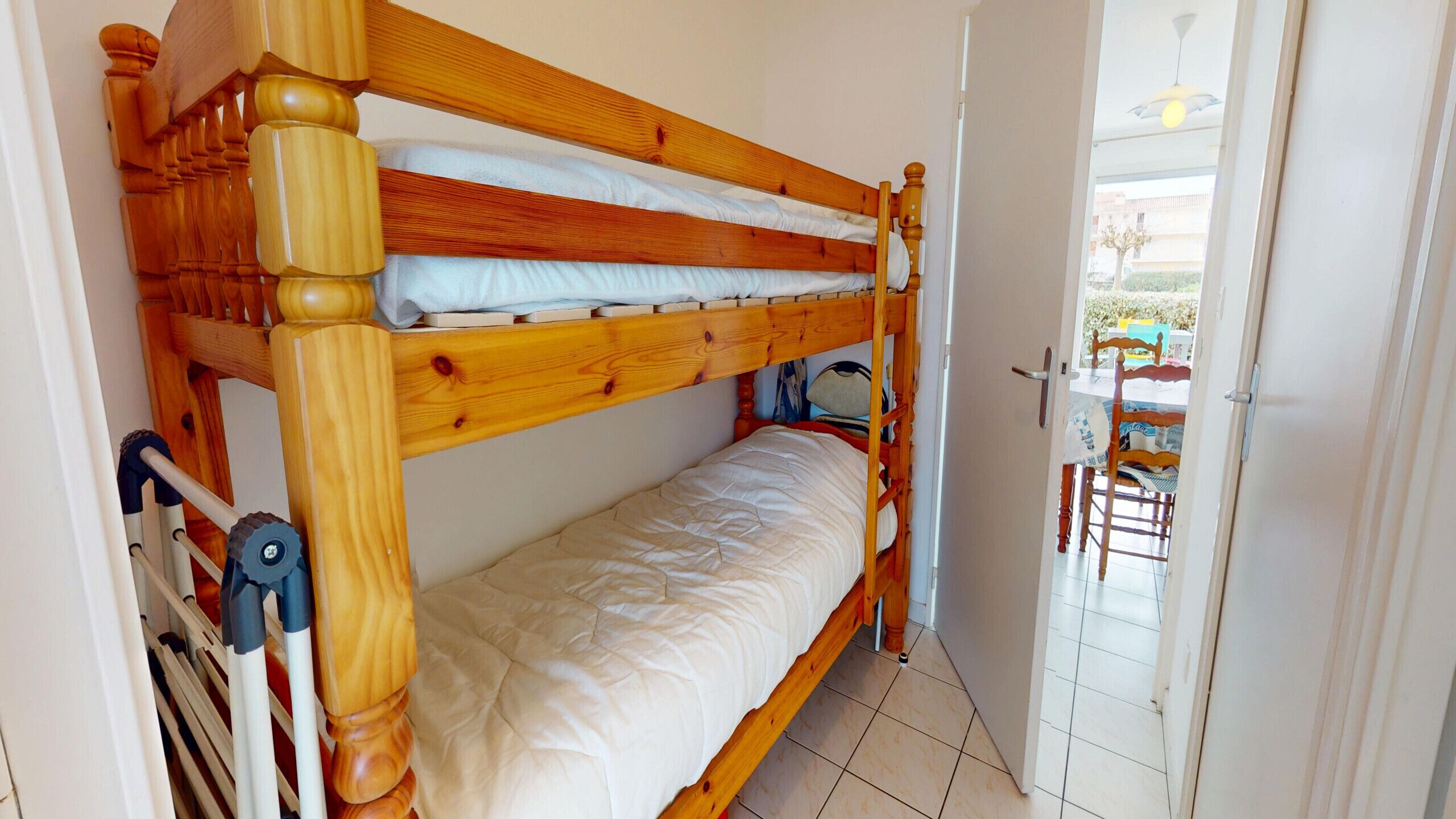 A bunk bed with a wooden headboard, a white mattress, and a wooden floor.