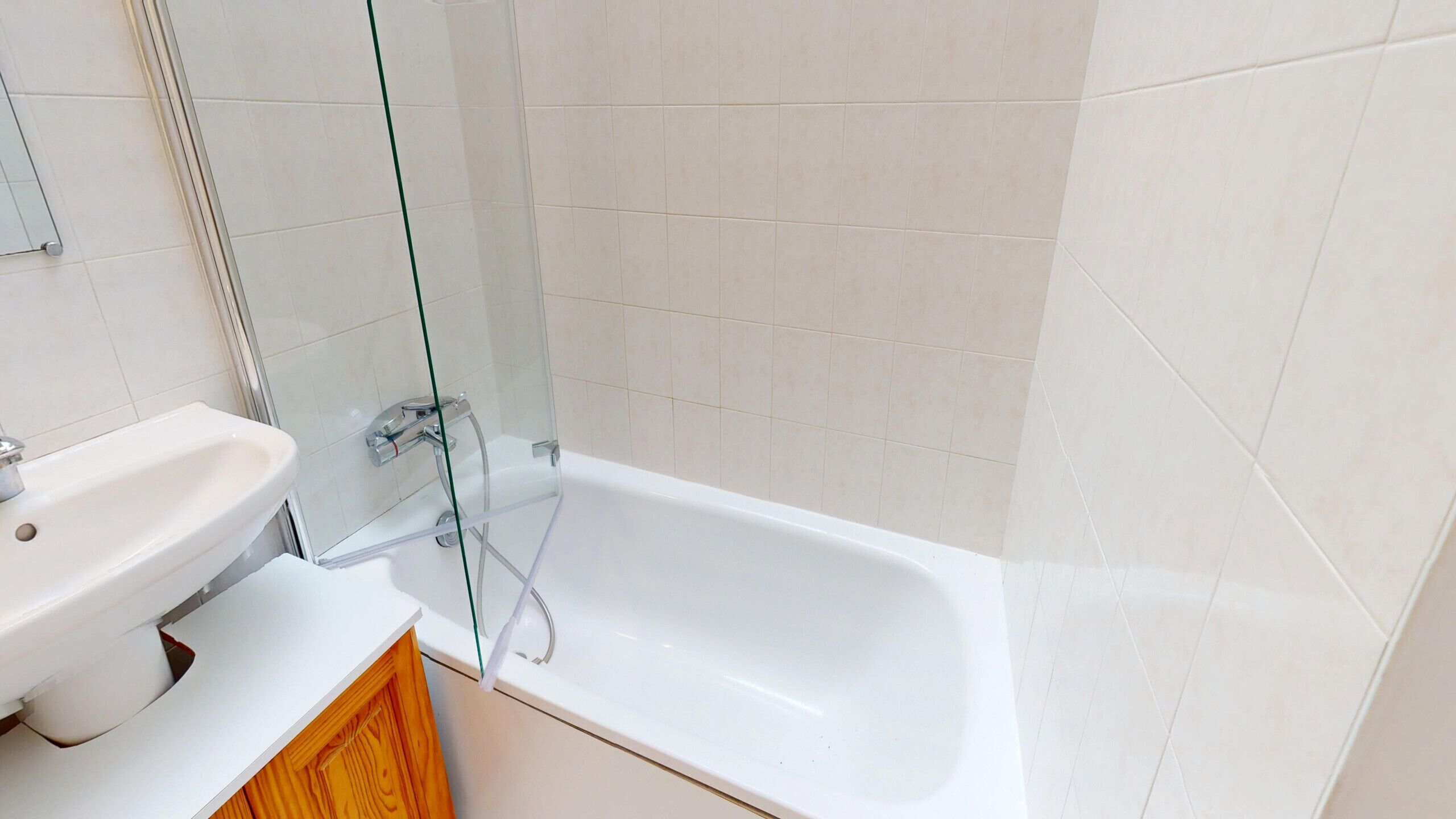 A bathroom with a white sink, a glass shower enclosure, and a white bathtub.