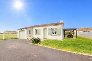 A single-story house with a covered patio, a fenced yard, and a clear sky. - Parenthese du Patis - House for 6 + enclosed garden (Saint-Hilaire-de-Riez)
