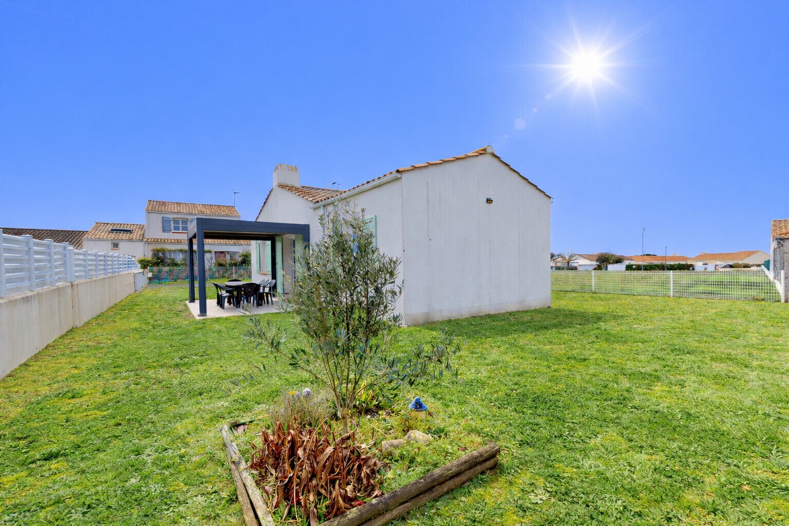 Propiedad residencial con un porche cubierto, un jardín pequeño y un edificio blanco.