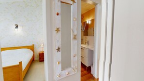 Ein Schlafzimmer mit Bett, Nachttisch, Spiegel mit Sterndekoration sowie ein Badezimmer mit Waschbecken und Spiegel.