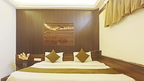 A hotel room with a wooden headboard, a large bed with white bedding, and a wall-mounted artwork. - Hotel Hilife (New Delhi)